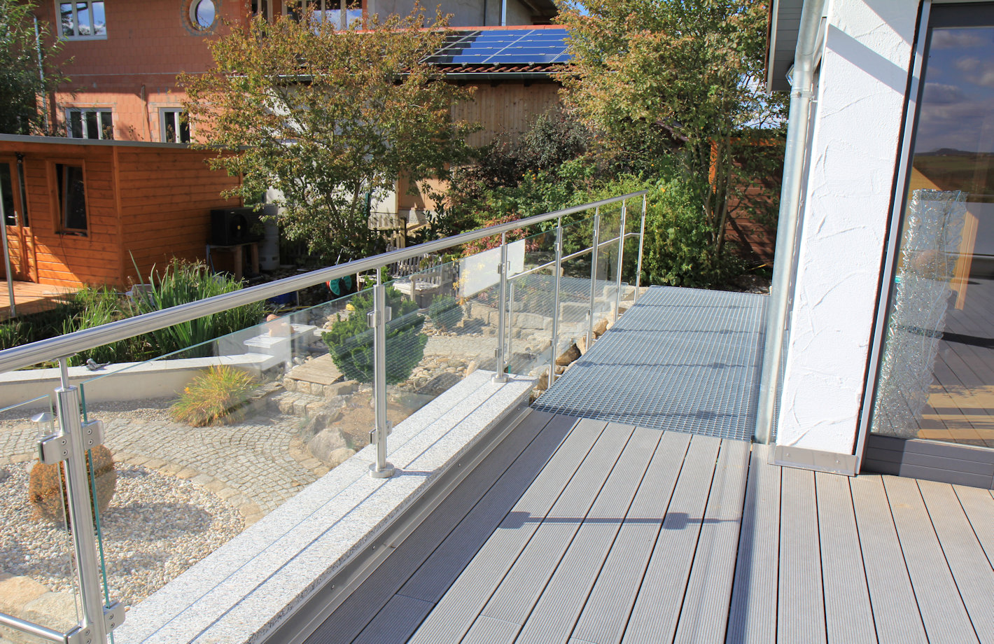 Brüstungsgeländer aus Edelstahl und Klarglas mit Ausblick in den Garten