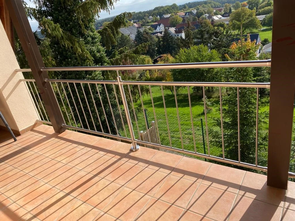 Stabgeländer aus Edelstahl zwischen Holzpfosten auf dem Balkon montiert